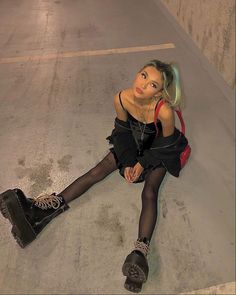 a woman sitting on the ground with her legs crossed wearing black tights and boots