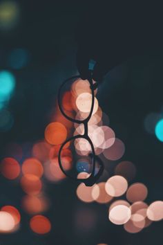 a pair of glasses hanging from a string with blurry lights in the back ground