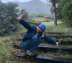 a woman sitting on some steps in the rain with her arms up and hands out