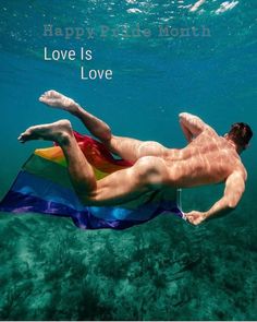 a man swimming in the water with a rainbow flag under his arm and feet up