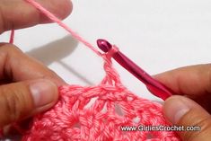 two hands crocheting the end of a piece of pink yarn with a hook