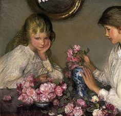 two women sitting at a table with pink flowers in front of a painting on the wall