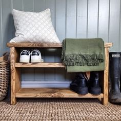 a wooden bench with two pairs of shoes and a blanket on it next to some boots