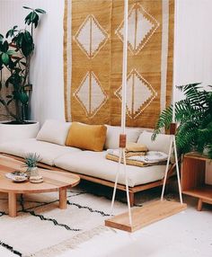 a living room filled with lots of furniture next to a wall hanging plant and potted plants