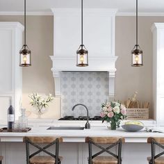 a kitchen with four stools in front of an island and three lights above it