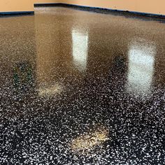 a shiny black floor with white speckles on the top and bottom, in an empty room