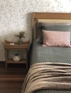 a bed sitting next to a night stand on top of a wooden floor