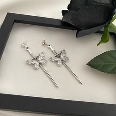 Handmade gothic earrings featuring silver metal swords with intricate butterfly details, paired with black polymer clay roses. These dangle drop earrings are a unique blend of vintage and gothic style, perfect as a statement piece or gift for her.  *Each pair measures 12 x 2 cm (4,7 x 0,8 inch) and weighs just 10 g, making them lightweight and comfortable to wear.  *Since these earrings are handmade, each flower may vary slightly from the one shown in the photo  *Our earrings come with two fastening options: clip-on earrings or ear wires, ensuring a perfect fit for everyone. *We take great care in packaging and shipping orders to ensure safe and fast delivery. However, in order to maintain affordable prices for our customers, we reserve the right to ship some packages without tracking. *Pl Clay Roses, Butterfly Details, Drop Earrings Silver, Gothic Earrings, Gothic Style, Shipping Orders, Gothic Jewelry, Slovakia, Black Rose