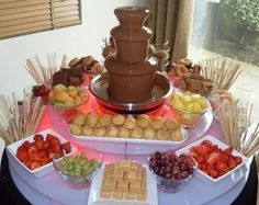 an assortment of desserts and snacks on a table in front of a large chocolate fountain