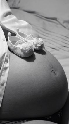 a pregnant woman's belly with her shoes on the top of it, in black and white