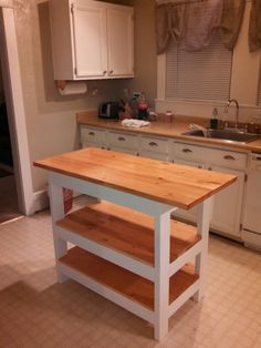 a kitchen with an island made out of two different pieces of wood and white cabinets