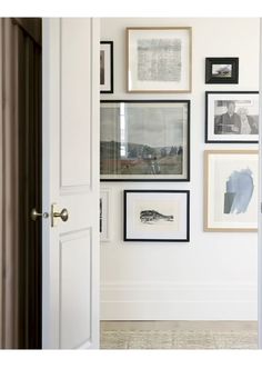 an open door with many framed pictures on the wall behind it and a white door