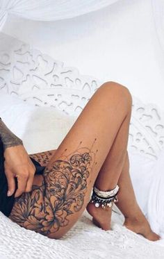 a woman laying on top of a bed next to a white sheet covered in tattoos