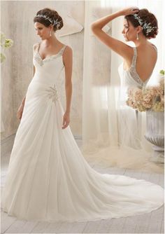 a woman in a white wedding dress looking at her reflection in the mirror while wearing a bridal gown