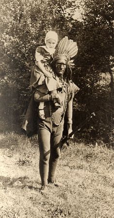 an old black and white photo of a woman carrying a child on her back