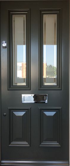 a black front door with two sidelights and blinds on the window sill,