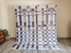 an old quilt is on display in a room with wood floors and a wooden table