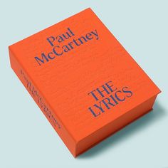 an orange book with blue lettering on the front and back cover that reads paul mccartney