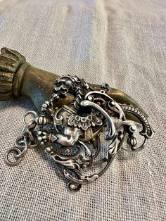 an ornate metal object is laying on a cloth covered tablecloth with a chain attached to it