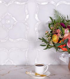 a bouquet of flowers sitting on top of a table next to a cup of coffee