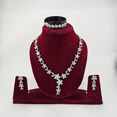 a necklace and earring set is displayed on a red display stand with white flowers