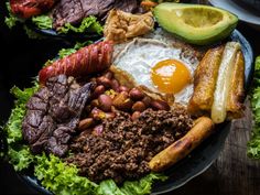 a plate with meat, beans, avocado and an egg on it next to other foods