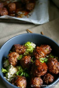 a bowl filled with meatballs and broccoli on top of rice next to chopsticks