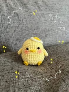 a crocheted yellow bird sitting on top of a gray couch next to stars