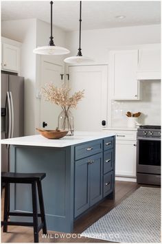 a kitchen with blue cabinets and an island in front of the stove, sink and refrigerator