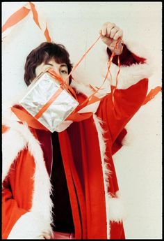 a man dressed as santa clause holding a wrapped present