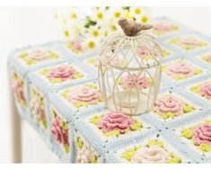 a crocheted table cloth with a bird in a cage on top of it