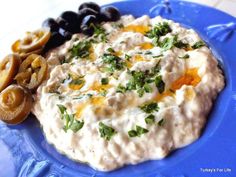 a blue plate topped with hummus and olives