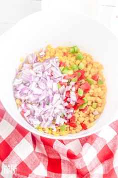 a white bowl filled with chopped vegetables on top of a red and white checkered table cloth