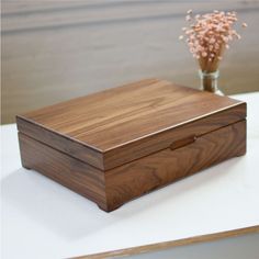 a wooden box sitting on top of a table next to a vase filled with flowers