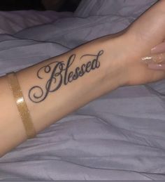 a woman with a tattoo on her arm that reads, blessing and is laying in bed