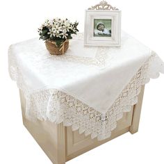 a table topped with a basket of flowers next to a photo frame and potted plant