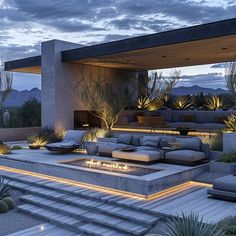 an outdoor living area with couches, fire pit and cactus plants at dusk time