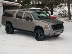 a silver truck parked in front of a garage with snow on the ground and trees