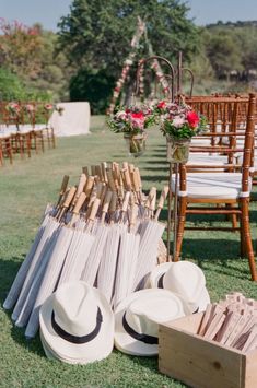 an outdoor ceremony set up with hats, flowers and other items on the grass in front of chairs