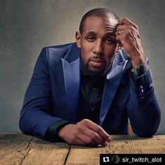 a man in a blue suit sitting at a table with his hand on his head