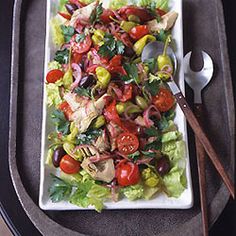 a square plate filled with salad on top of a table