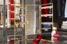 an assortment of jewelry on display in a store window with red velvet chairs and other items