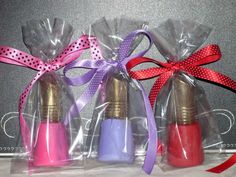 three pink and purple bottles wrapped in cellophane with bows on them, sitting next to each other