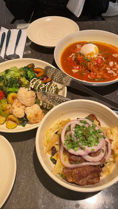 three bowls of food on a table with utensils