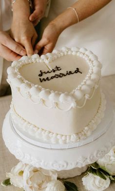 a bride and groom cutting their wedding cake with the words just married written on it