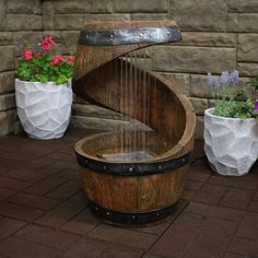 a wooden barrel with water running down it and some potted plants next to it