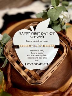 an apple shaped plaque with the words happy first day of school written on it next to some flowers