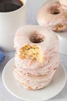 three glazed donuts stacked on top of each other next to a cup of coffee