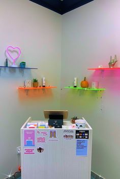 a small refrigerator sitting in the corner of a room next to shelves with items on them