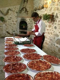 a man in an apron is preparing pizzas on a table with many pans